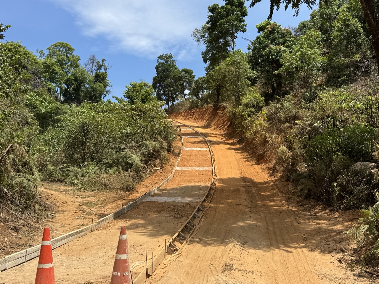 Fresh earthworks on the ridge — orange cones, no traffic.