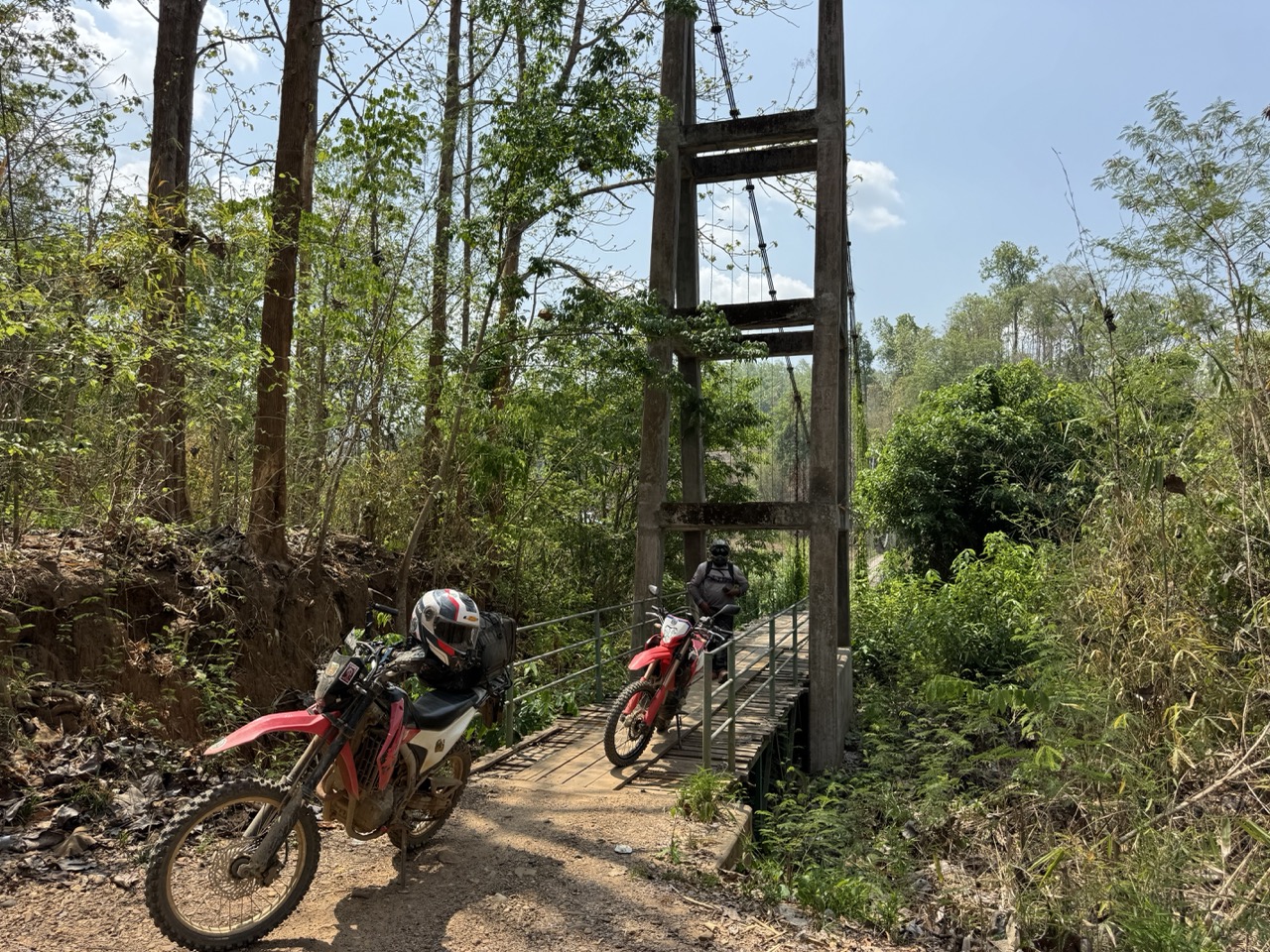 Bikes at the foot of a long pedestrian suspension bridge.