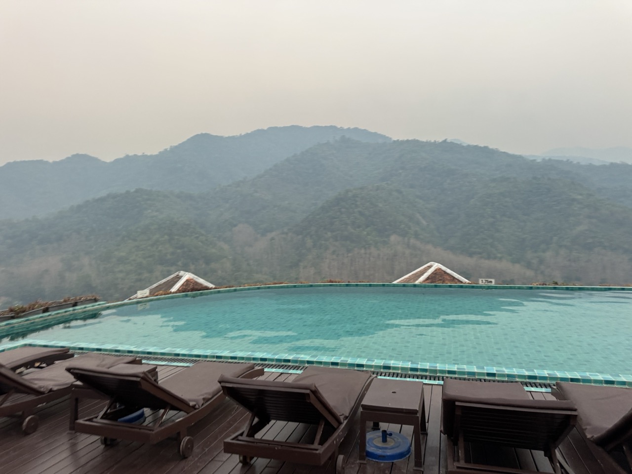 Le Grand Pakbeng's infinity pool above the Mekong — the misty mountains on the far side are Thailand.