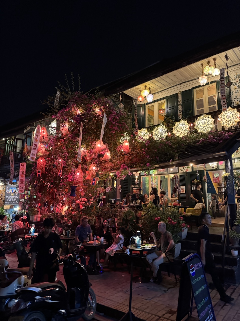 Night street lit by Pi Mai lanterns and bougainvillea. We walked into town for dinner and got soaked.
