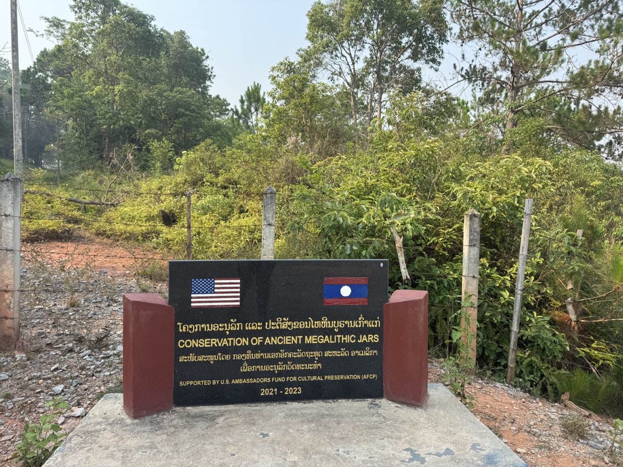 Conservation plaque with small US flags. The clearance work is part of why visitors can walk Site 2 at all.