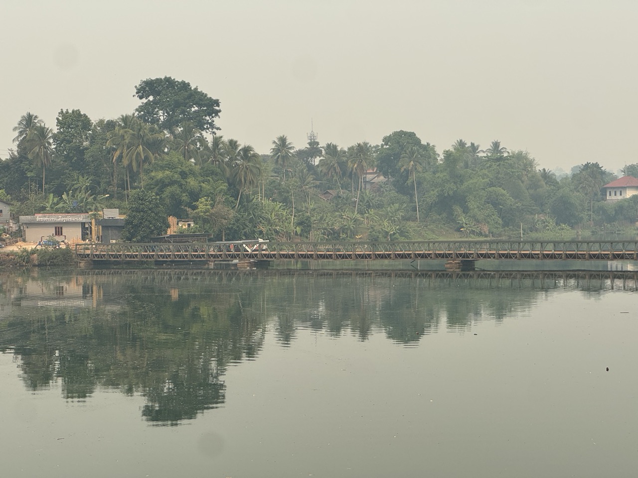 Bailey bridge over a Mekong tributary, reflecting in the still water below.