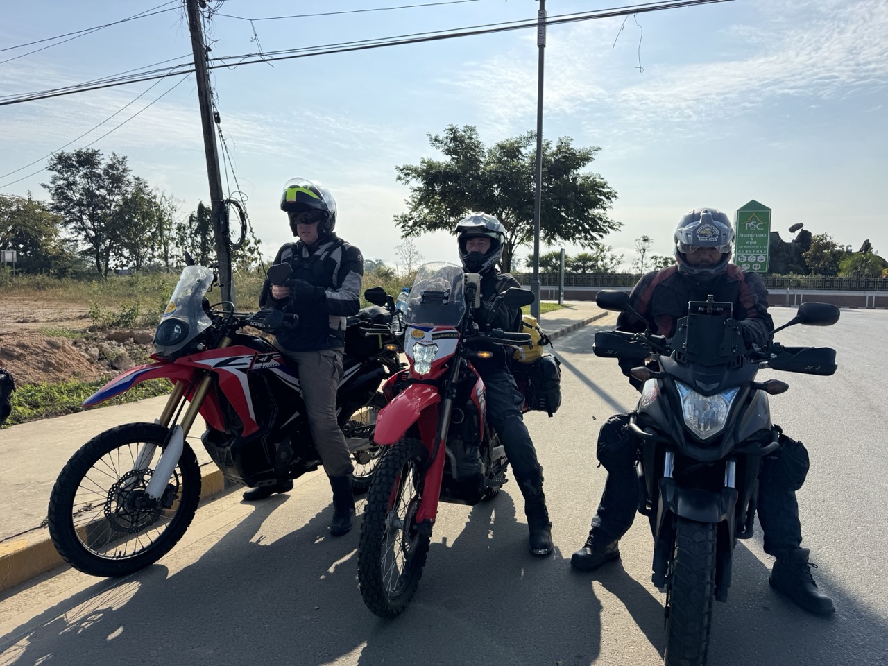 Three of the group at the Tonpheung exit — two CRFs and the CB500X, helmets still on. The other two had pushed ahead.