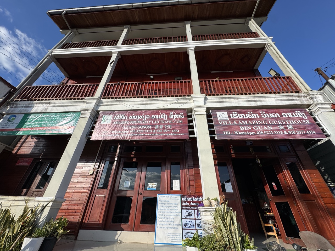 Villa Amazing Maison Guesthouse — three-storey wooden building with trilingual signage in Lao, English, and Chinese. Our base for the night.