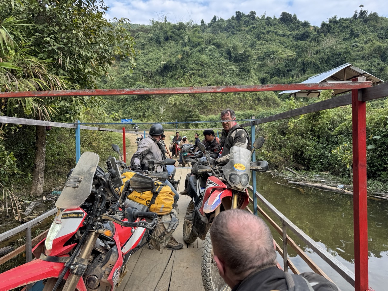 Aboard the Nam Ou ferry into Muang Khua — a jam-packed metal barge with bikes, scooters, and standing-room people sharing the deck.