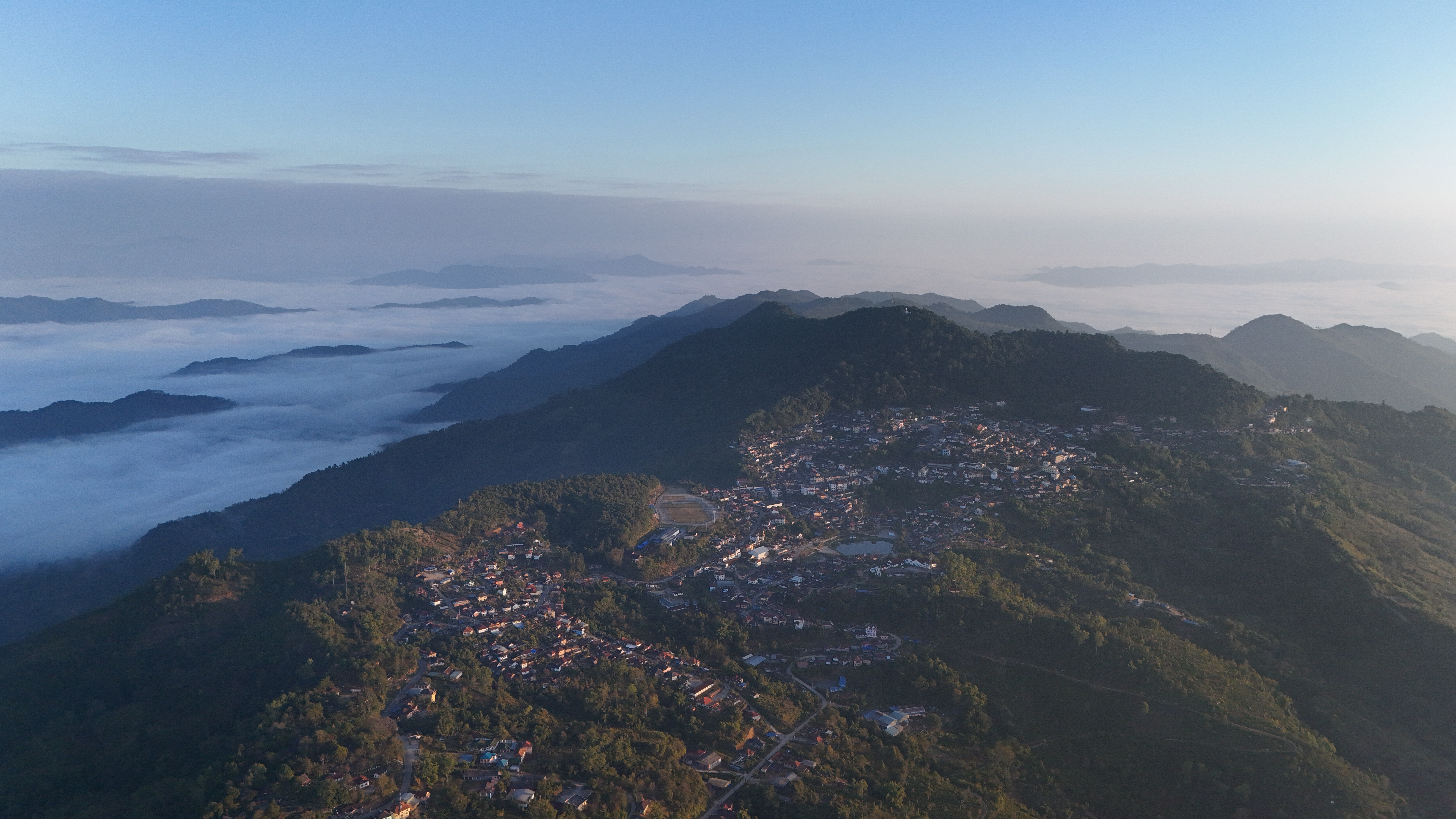 Same morning, wider angle — the town wrapped in valley mist with the ridges of the Chinese border in the distance.