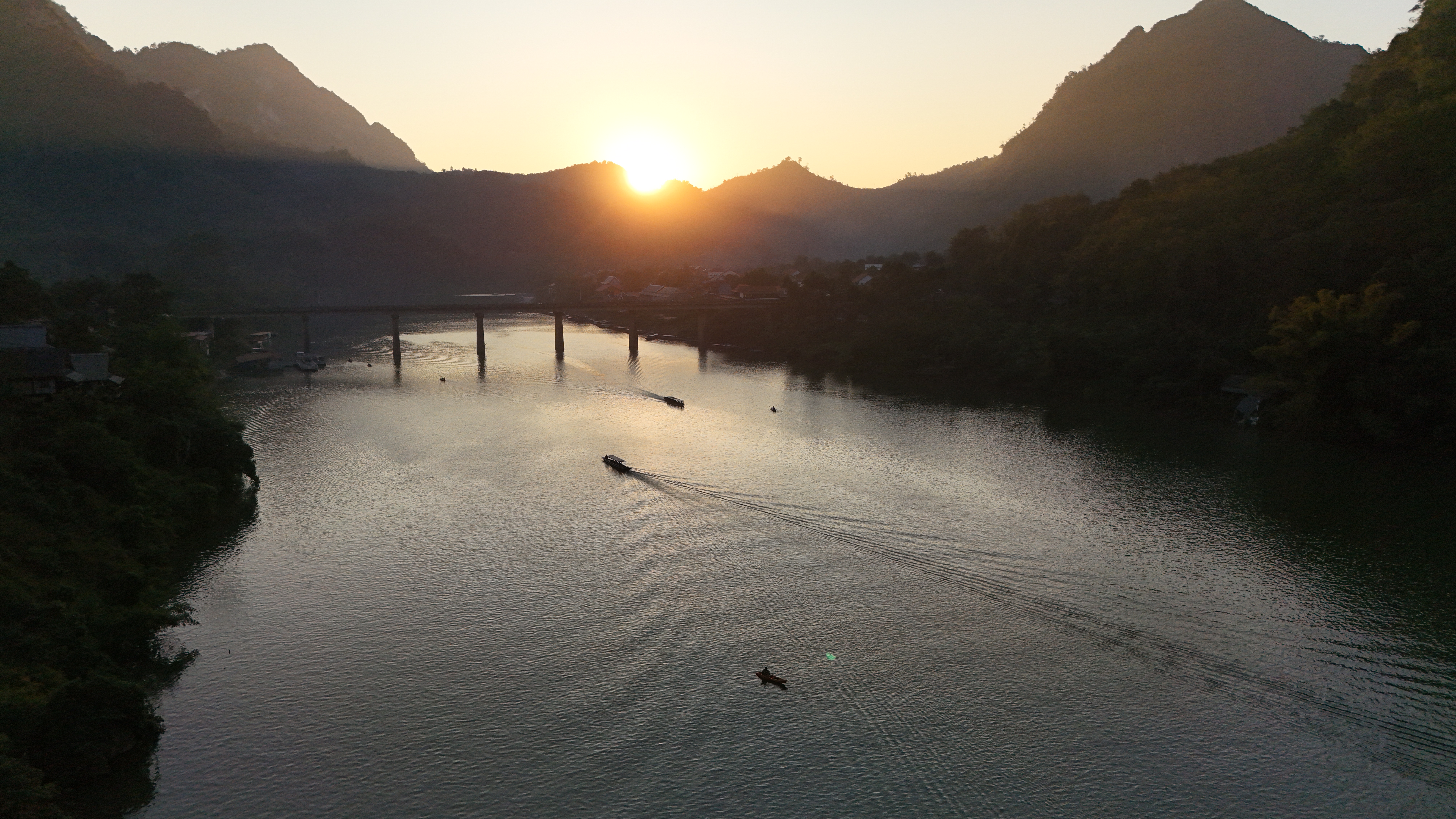 Nong Khiaw from higher up — the bridge, the river bend, and the wall of karst peaks that rings the village.