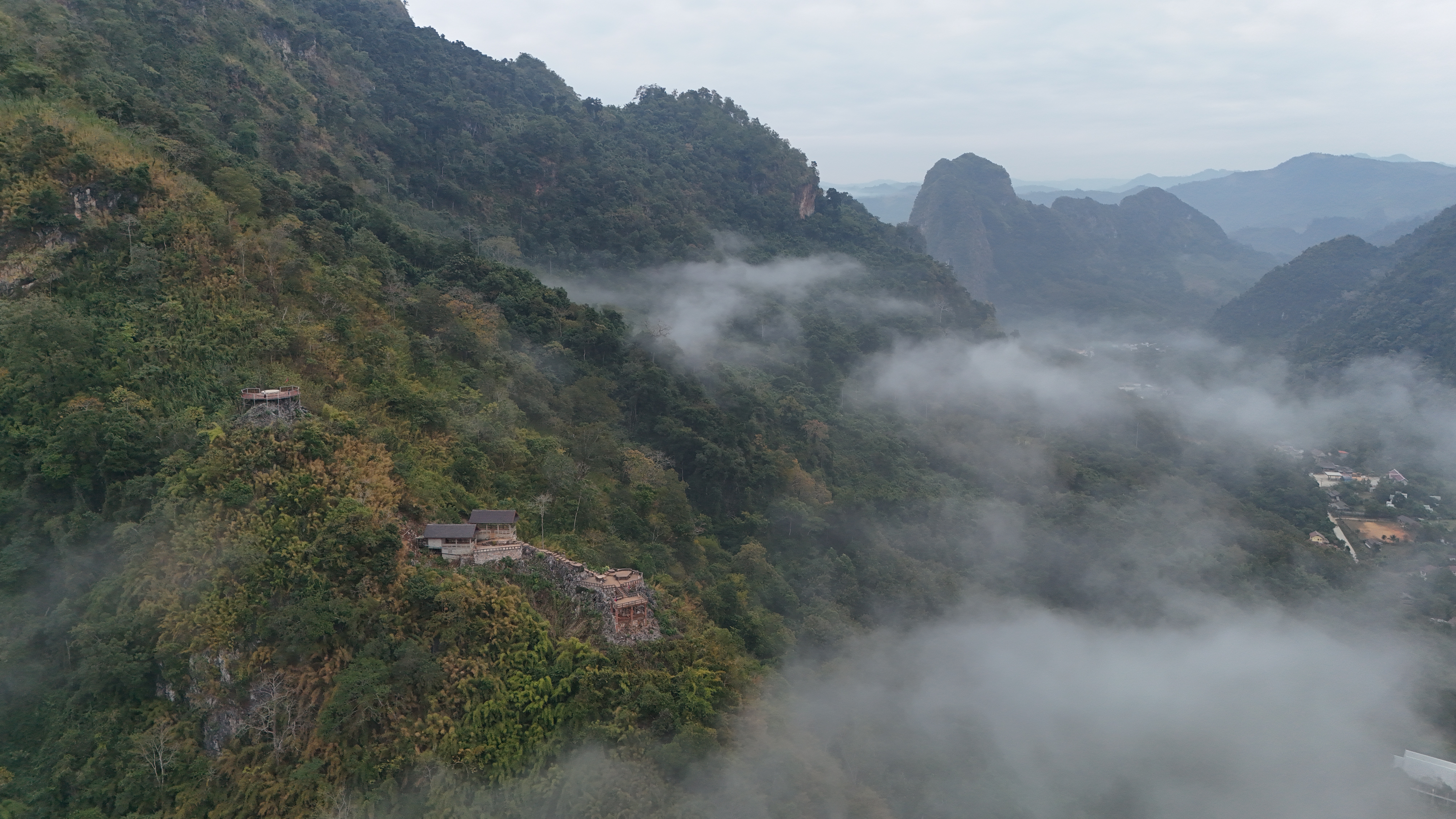 Same morning, different angle — the Nam Ou snaking south through the karst as the sun starts to lift the fog.