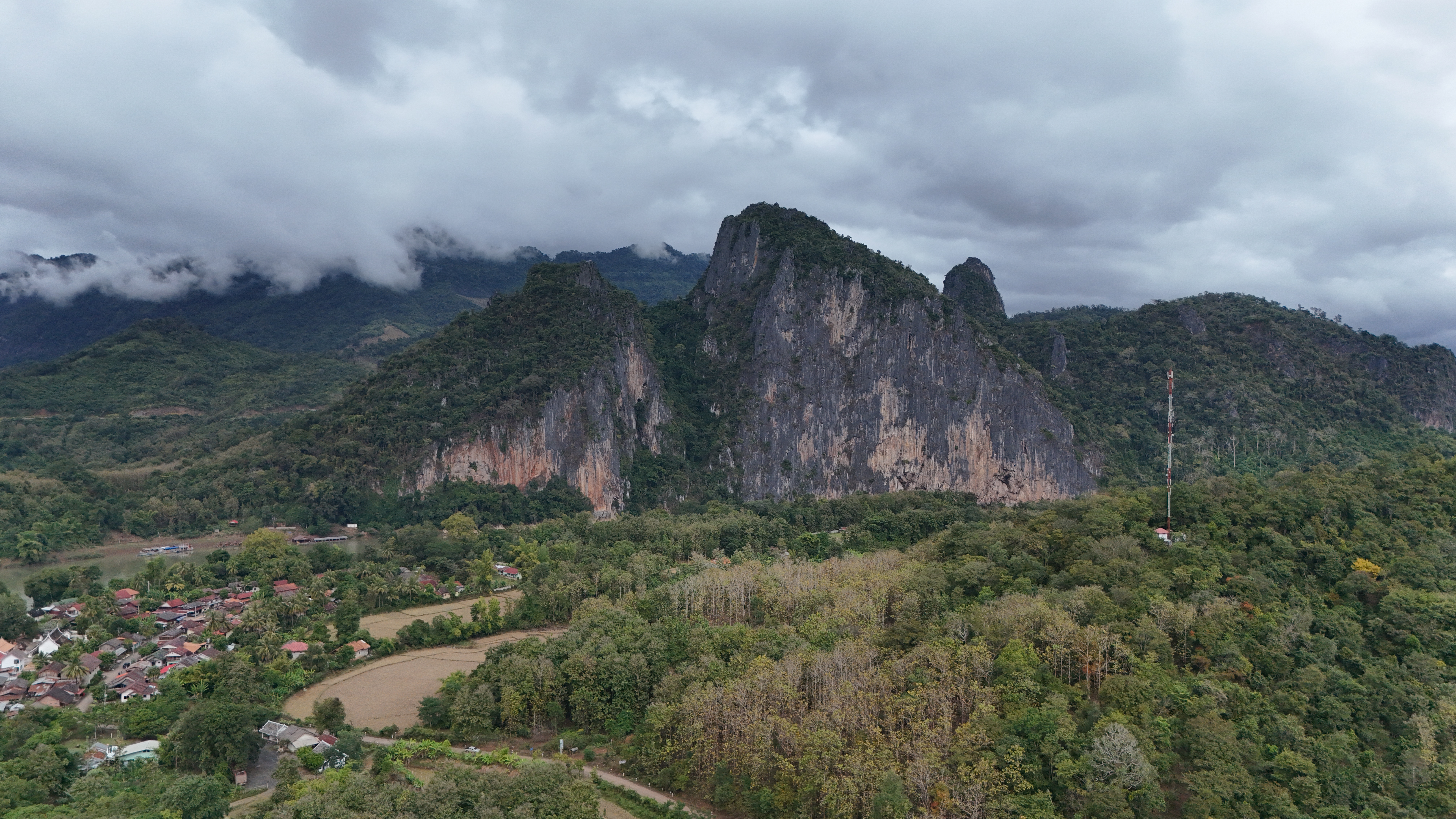 Pak Ou cliffs from the drone — Buddha statues are tucked into caves at the base of these walls.